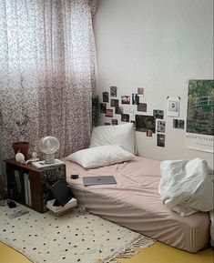 a small bed in a room with pictures on the wall and a laptop computer sitting on top of it