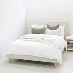 a bed with white sheets and pillows in a room