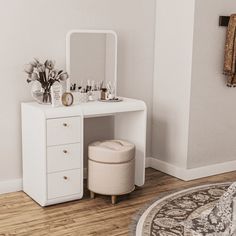 a white dressing table with drawers and stools in a small room next to a rug