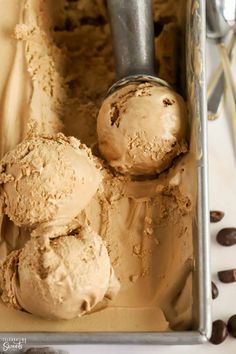 three scoops of ice cream in a metal container with chocolate chips on the side