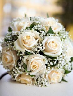 a bouquet of white roses sitting on top of a table