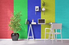 a room with a desk and chair in front of a rainbow colored wall that has a laptop on it