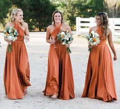 bridesmaids in orange dresses laughing and holding bouquets at the same time as they walk down the road