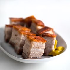 slices of pork with mustard on a white plate