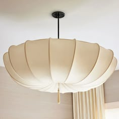 a light fixture hanging from the ceiling in a living room with drapes draped around it