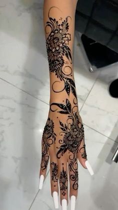 a woman's hand with black and white henna tattoos on her left arm