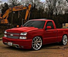 a red truck parked in front of a construction machine