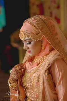 a woman in a bridal gown and veil with jewelry on her head, looking at something