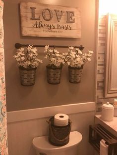 a bathroom with three buckets filled with flowers on the wall next to a toilet