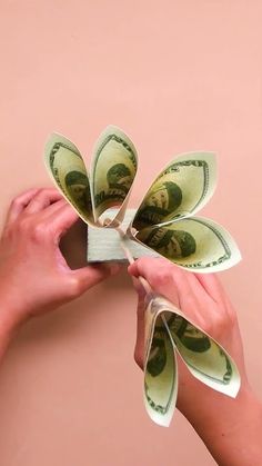 two hands are holding dollar bills in one hand and another is wrapping them around the other