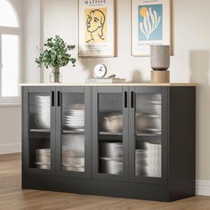 a black cabinet with glass doors and pictures on the wall