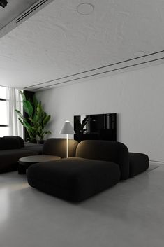 a living room filled with black couches and a white table next to a window