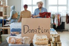 a donation sign sitting on top of a table next to stacks of cans and boxes