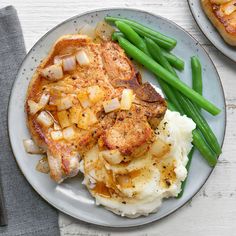 a plate with mashed potatoes, green beans and meat on it next to a fork