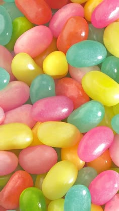 there are many jelly beans in the bowl and one is pink, green, yellow, and blue