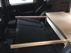 the interior of a vehicle with an open drawer on the back seat and wooden table in the passenger area