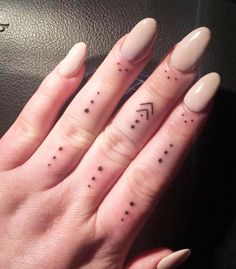 a woman's hand with two small tattoos on her fingers and the other finger