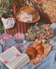 there is a basket with flowers and pastries on the ground next to an open book