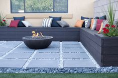 a fire pit sitting in the middle of a patio surrounded by plants and pillows on top of it