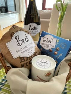 a basket filled with wine and chocolates next to a bottle of wine on top of a table