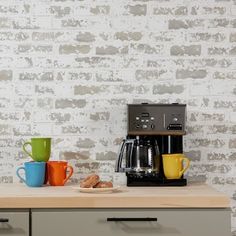 a coffee maker sitting on top of a counter next to two mugs and a toaster