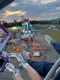 people are riding on the ferris wheel at an amusement park as the sun goes down