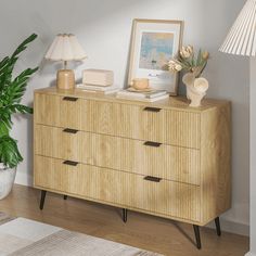 a wooden dresser sitting next to a potted plant on top of a hard wood floor