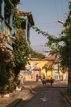 an empty street with two people sitting at a table in the middle and some trees on either side