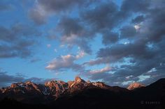 the mountains are covered in clouds as the sun goes down on them and there is no image to provide a caption for