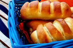 two loaves of bread sitting in a blue basket on a wooden table next to an orange napkin