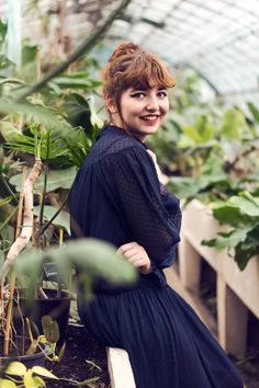 a woman sitting on a bench in a greenhouse