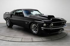 a black muscle car is on display in a room with white walls and flooring