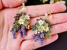 a hand holding two small flower earrings in it's palm