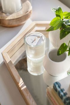 a white clock sitting on top of a glass table next to a potted plant