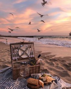 a picnic on the beach with seagulls flying over it and food in a basket