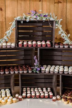 an assortment of cupcakes on display in wooden crates