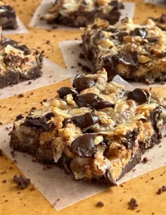 there are many pieces of chocolate and nuts on top of the brownie squares that have been cut in half