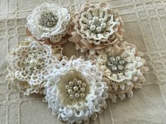 several crocheted flowers sitting on top of a white cloth covered tablecloth,