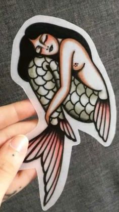 a person holding up a sticker with an image of a mermaid on it's back