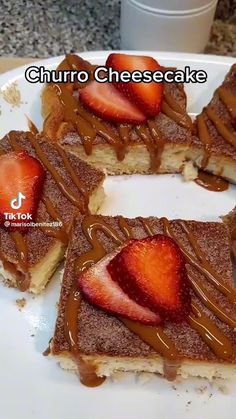 four slices of cheesecake with chocolate sauce and strawberries on top, sitting on a white plate