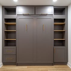 an empty room with gray cabinets and gold handles on the doors is lit by recessed lights