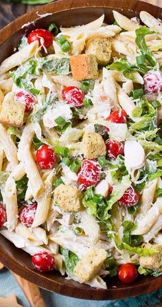 a wooden bowl filled with pasta salad on top of a table