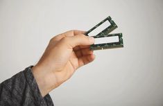 a person holding up four pieces of electronic circuit board in their hand, against a white background