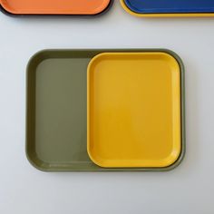 three different colored trays sitting next to each other on top of a white table