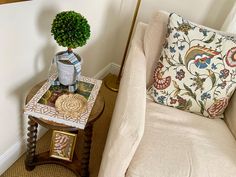 a small table with a potted plant on it next to a couch