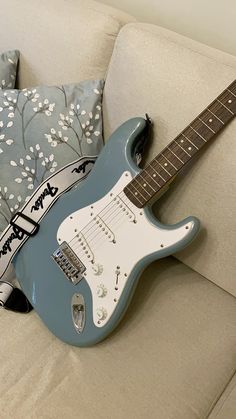 a blue electric guitar sitting on top of a couch next to pillows and a pillow