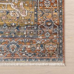 an orange, blue and yellow rug with fringes on the bottom is laying on a wooden floor