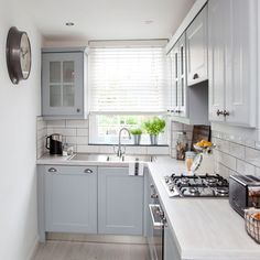 a kitchen with white and gray cabinets, an oven, sink and radiator