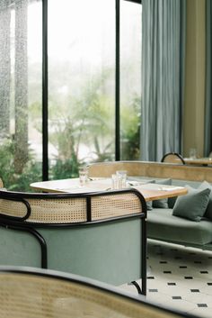 the inside of a restaurant with tables, chairs and couches in front of large windows