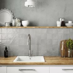 a kitchen with white cabinets and counter tops, gray tile backsplash and wooden shelves